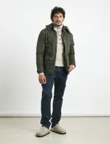 Campera de abrigo color verde militar, con capucha desmontable forrada, cierre frontal con cremallera y botones a presión. Cuenta con múltiples bolsillos: dos en el pecho con cierre, dos en la cintura con botones y un bolsillo en la manga. El interior está forrado para mayor calidez.