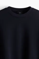 Buzo de cuello redondo color negro, con diseño liso, hombros caídos y puños y dobladillo acanalados.