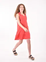 Vestido corto color rojo, de corte recto y holgado, con escote en V y tirantes anchos formados por lazos para atar en los hombros. Cuenta con un volante sutil en el ruedo.