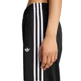 Pantalón deportivo Adidas de la línea Originals, confeccionado en tejido tricot de poliéster reciclado. Presenta un corte holgado con cintura media elástica, bolsillos laterales con cierre y el icónico diseño de las tres tiras blancas a lo largo de las piernas.