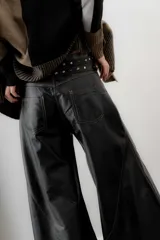 Pantalón de cuero ovino italiano de tiro medio y corte ancho. Presenta costuras diagonales en las piernas que aportan volumen y vuelo, con pretina y pasacintos confeccionados en gamuza al tono.