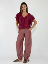Pantalon de lino color bordo, de corte ancho y holgado, con bolsillos laterales y detalles de cordón ajustable en los tobillos.