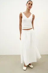 Top de punto canalé en color beige, con escote en pico adornado con una delicada aplicación de encaje blanco y tirantes anchos.