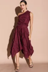 Falda midi asimétrica color bordó, con volados decorativos en espiral y cierre lateral.