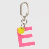 Llavero con dije en forma de letra A color rosado y pequeño dije circular amarillo con logo de la marca grabado. Incluye gancho metálico tipo mosquetón.