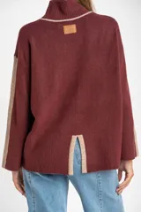 Sweater de punto con cuello alto, diseño oversize y mangas largas. Presenta un contraste de color en el cuello y una franja vertical en las mangas en tono beige.