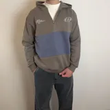 Canguro con capucha y cierre frontal parcial, de diseño color block en tonos marrón y azul. Presenta detalles estampados en el pecho y corte estándar.