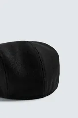 Boina de estilo clásico con visera corta, confeccionada en tejido de lana color marrón oscuro.