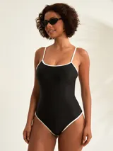 Malla entera negra con finos breteles y ribetes blancos en contraste a lo largo del escote y las piernas.