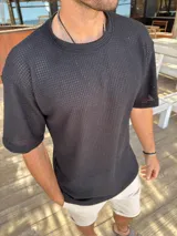 Remera de tejido de punto con textura calada, color negro, de corte oversize y manga corta.