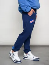 Pantalón deportivo azul claro con puños ajustados en los tobillos. Presenta el escudo del Club Nacional de Football bordado en la pierna izquierda y el logo de Umbro bordado en la derecha.
