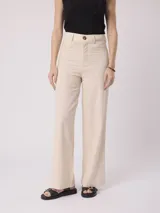 Pantalón de corte recto y tiro alto color beige, confeccionado en mezcla de algodón y lino, con cierre frontal de botón y trabillas para cinturón.
