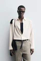 Camisa de hombre de corte relajado (relaxed fit) en tejido de mezcla de algodón y viscosa, color beige claro con finas rayas verticales. Presenta cuello italiano y manga larga con puño abotonado.