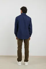 Camisa de manga larga en color azul oscuro con estampado de micro puntos claros. Presenta cuello con botones, cierre frontal abotonado y puños ajustables.