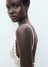 Top halter blanco de crochet con diseño entallado, espalda abierta con tirantes finos cruzados y detalles de ondas en los bordes.