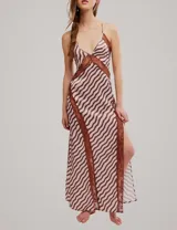 Vestido largo con estampado de ondas en tonos rosa y marrón, con detalles de encaje marrón en el escote y aberturas laterales, tirantes finos y tajo profundo en la pierna.