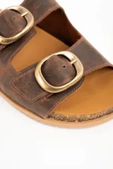 Sandalias de doble hebilla en cuero marrón con acabado texturizado, plantilla cómoda y suela tipo corcho con base de goma antideslizante.