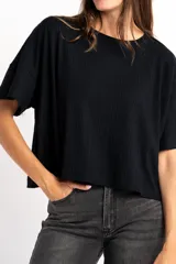 Remera de corte oversize, confeccionada en tejido de viscosa con textura acanalada, de color negro, con mangas cortas y cuello redondo.
