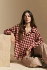 Camisa de estilo leñador con estampado de cuadros en tonos azul, negro y marrón. Presenta cuello clásico, cierre frontal con botones y mangas largas con puños abotonados.