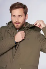 Campera de abrigo color verde militar, resistente al agua, con capucha desmontable, cierre metálico y botones a presión personalizados. Tiene bolsillos en el frente y dos bolsillos internos.
