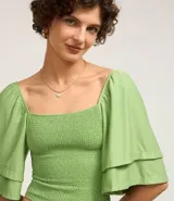 Blusa corta color verde claro con escote cuadrado y mangas cortas godê. Posee cuerpo en lastex, proporcionando un toque texturizado.