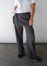 Falda gris con finas rayas verticales blancas, de corte mini y diseño cruzado con lazo lateral.