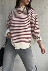 Sweater de punto con diseño a rayas horizontales en color rojo y crema, de corte holgado, cuello redondo y mangas largas con puños abotonados.