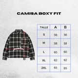 Camisa de manga larga con corte boxy fit, confeccionada en algodón a cuadros en tonos negro y gris. Presenta un bolsillo frontal en el pecho y el texto 'posta.' estampado en color blanco en la parte delantera.