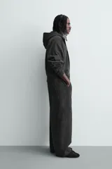 Sudadera con capucha y cierre frontal de cremallera, confeccionada en tejido de mezcla de algodón con interior afelpado. Presenta un diseño cropped, mangas largas, bolsillos frontales integrados en las costuras y acabados en rib. Posee un efecto lavado que le otorga una apariencia única.