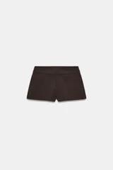 Bermudas de tiro medio y cintura ancha, color marrón, con bolsillos delanteros y cierre frontal con cremallera y ganchos metálicos.