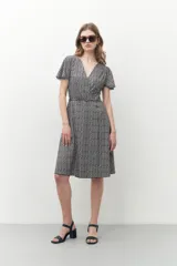 Vestido midi con estampado geométrico en blanco y negro, corte cruzado, mangas cortas y escote en V.