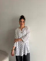 Blusa de viscosa de corte holgado, color blanco con estampado de lunares negros, escote en V con botones frontales y mangas tres cuartos.