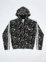Campera con capucha de estilo deportivo, confeccionada en tejido aterciopelado con estampado animal print de leopardo. Presenta cierre frontal, mangas largas con doble franja lateral blanca y puños elásticos.