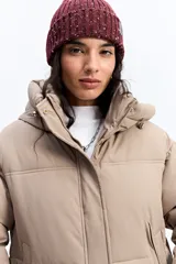 Campera puffer color crema con capucha, cuello alto, cierre frontal y puños elásticos.