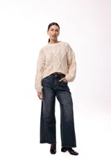 Sweater de tejido de punto grueso con diseño de rombos en relieve, cuello redondo y mangas largas amplias. Presenta una silueta relajada y holgada.