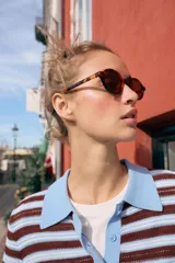 Top de punto de manga corta con diseño a rayas horizontales en tonos marrones y celestes, cuello polo liso en color celeste y cierre frontal con tres botones.