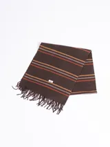 Bufanda de tejido suave en color marrón chocolate con diseño de rayas horizontales en tonos naranja, beige y gris. Presenta terminaciones con flecos en los extremos.