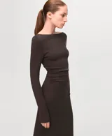 Vestido largo de corte ajustado en color marrón oscuro, con escote bote y mangas largas. Presenta un diseño minimalista con un sutil fruncido lateral en la cintura que realza la silueta.