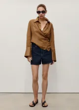 Short de jean de tiro alto con diseño recto y cinco bolsillos. Cuenta con cierre delantero de cremallera y botón, además de trabillas para cinturón.