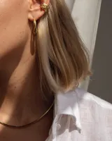 Gargantilla rígida de diseño minimalista, elaborada en metal dorado con acabado pulido, que se ajusta suavemente al cuello.
