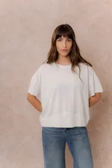 Remera oversize blanca de manga corta, con cuello redondo y recortes decorativos en el frente.