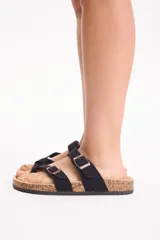 Sandalia plana de color tostado con diseño de tiras cruzadas y doble tira superior con hebillas metálicas ajustables, plantilla estilo corcho y suela negra.