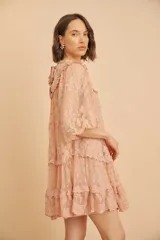 Vestido corto de encaje y tul color rosado, con diseño holgado, mangas largas abullonadas y detalles de volados en la falda.