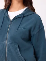 Canguro con cierre frontal y capucha, color gris con efecto desgastado. Presenta bolsillos laterales y logo bordado en el pecho.