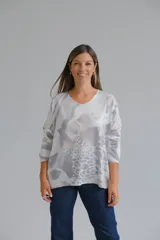Sweter de punto con escote en V y mangas largas, de corte holgado. Presenta un estampado abstracto en tonos grises y blancos con sutiles destellos brillantes.