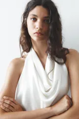 Top blanco de tejido satinado con cuello halter drapeado ajustable con lazada en el cuello y espalda descubierta con lazada.