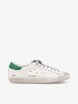 Zapatillas urbanas Golden Goose modelo Super-Star, de cuero blanco con detalles en verde en el talón y estrella en gris.