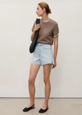 Short de denim celeste claro, con tiro medio, diseño de cinco bolsillos, presillas para cinturón y bajo deshilachado con pequeña abertura lateral.
