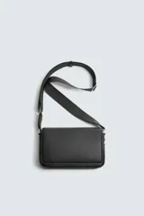 Bandolera negra con textura grabada, compartimento principal con cierre de solapa imantada, bolsillo interior con cremallera y asa de hombro ajustable.
