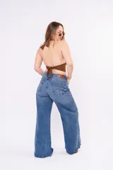 Jean de corte wide leg con costura central vertical en ambas piernas. Presenta un tono denim clásico, tiro medio y cierre frontal con botones.